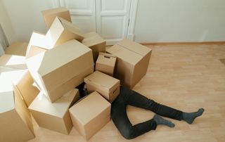 man-onder-verhuisdozen